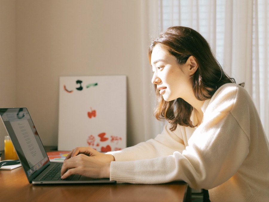 自宅のデスクでノートPCに向かって日本語でお願いする女性